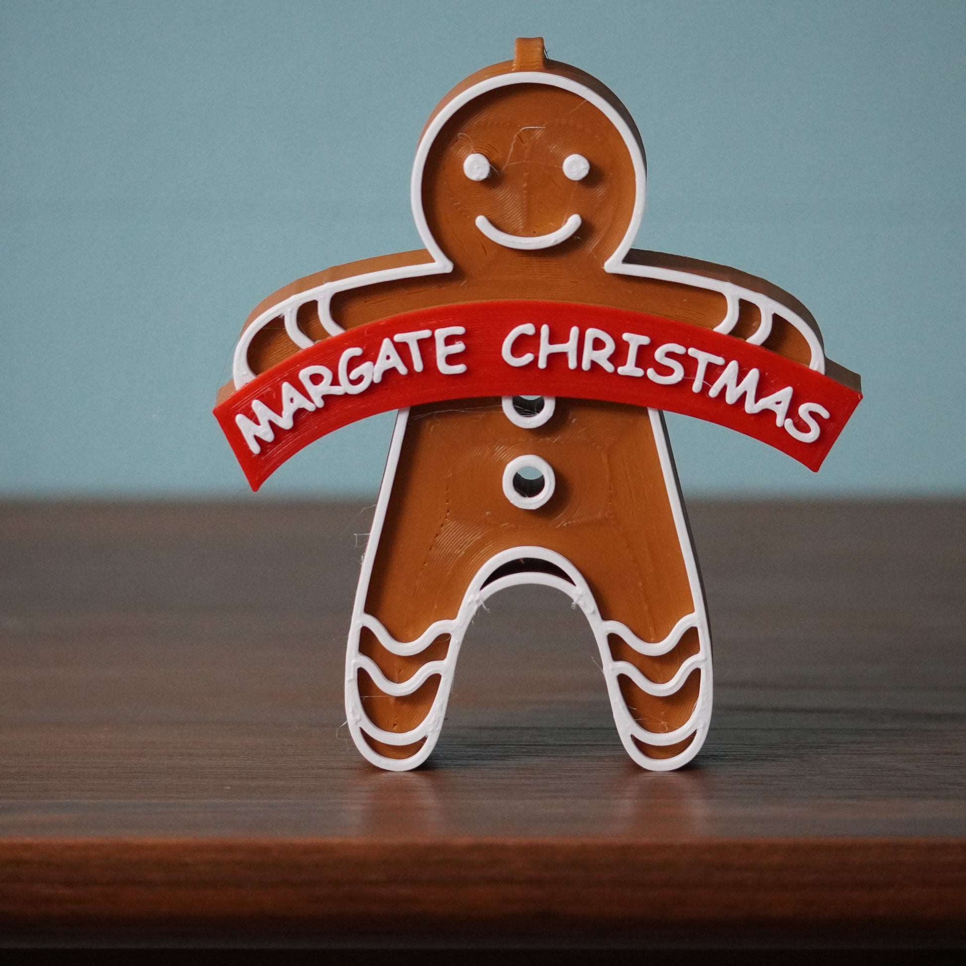 A Christmas ornament featuring a Margate design with a hanging hole on top.
