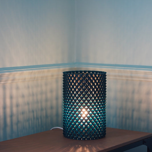 a lamp made of small shell like shapes that that casts shadows 