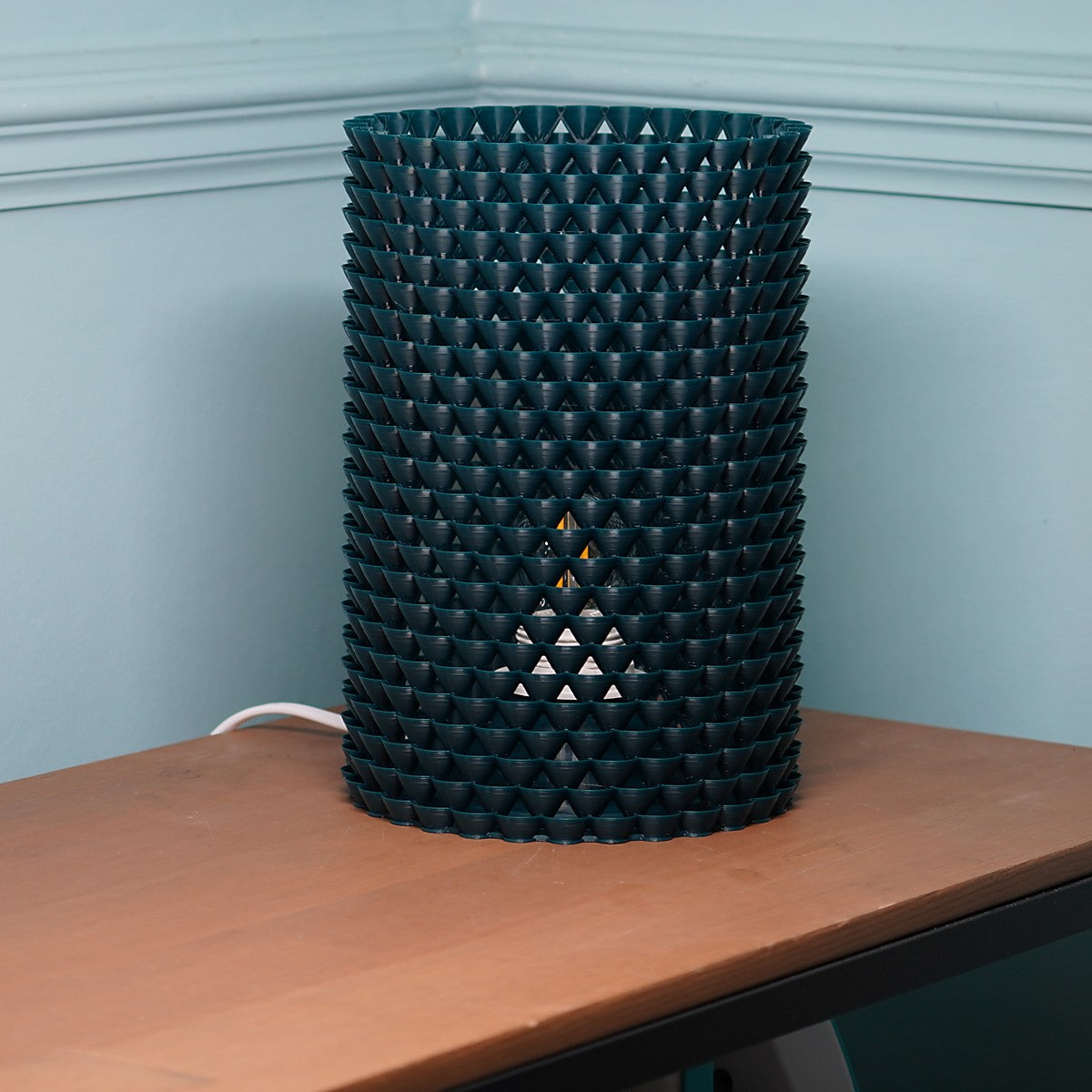 a lamp made of small shell like shapes that that casts shadows 