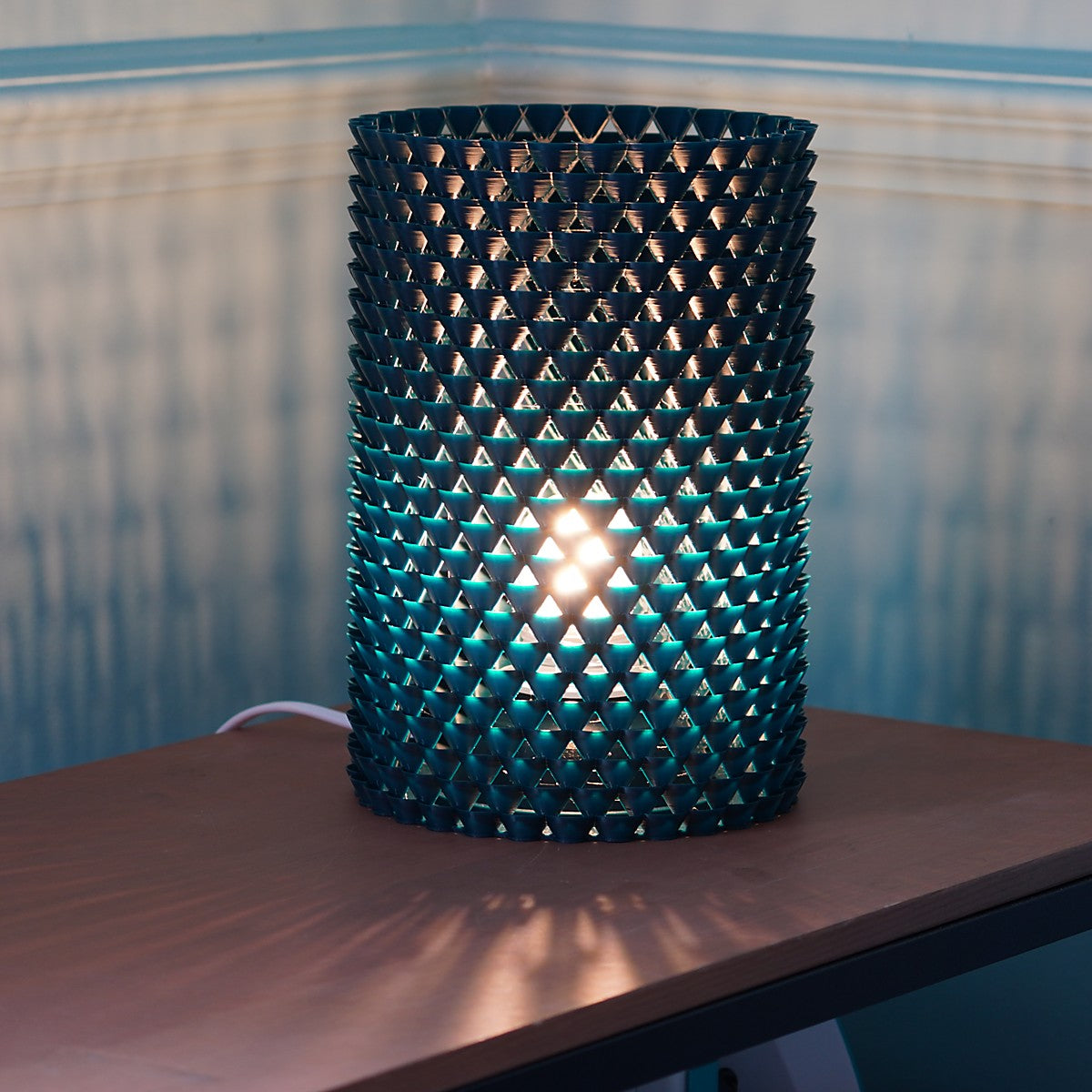 a lamp made of small shell like shapes that that casts shadows 