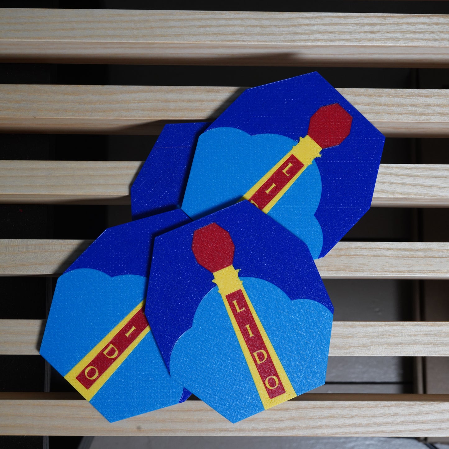 Blue and red coasters with 'Lido' branding on a wooden surface