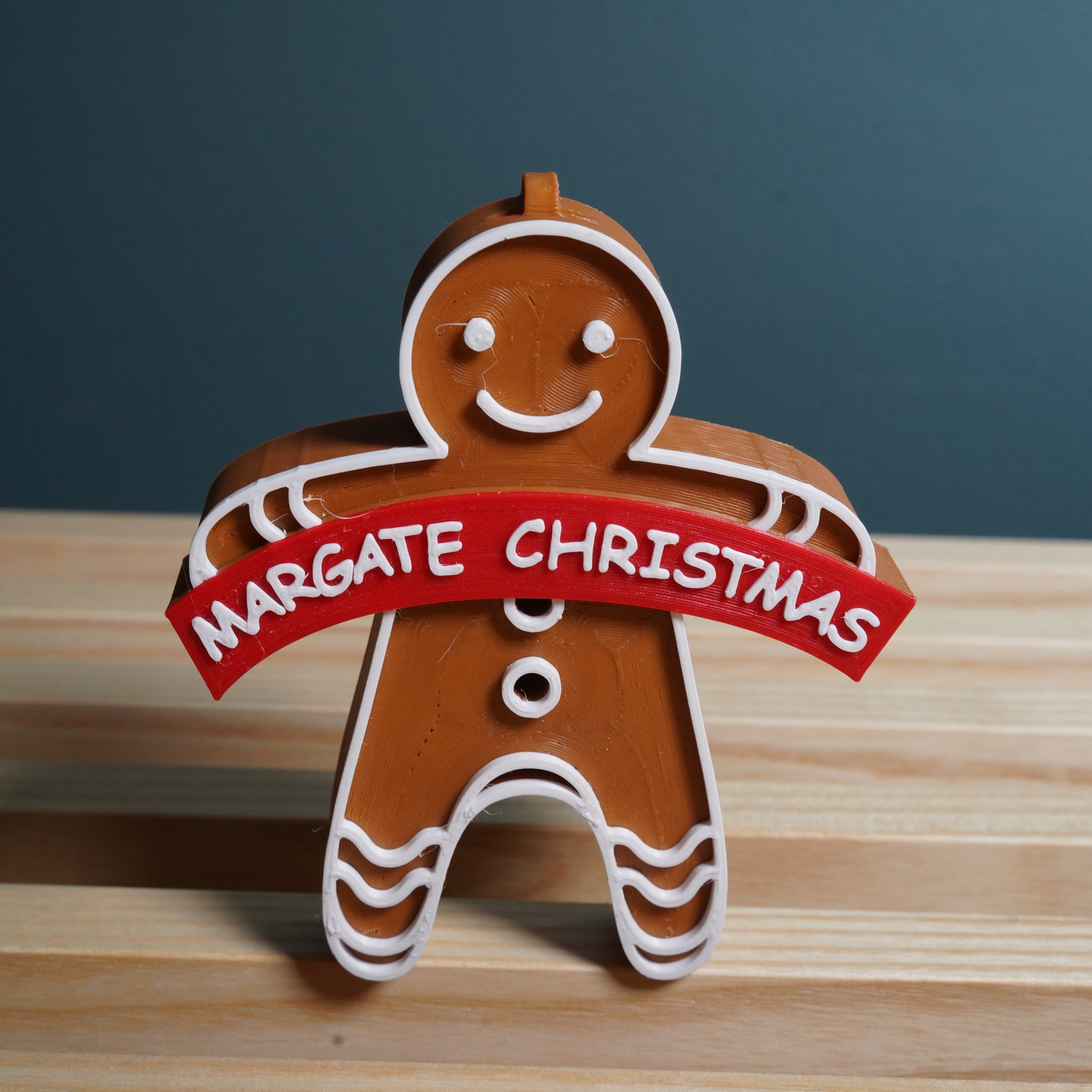 Gingerbread man decoration with 'Margate Christmas' banner on a wooden surface