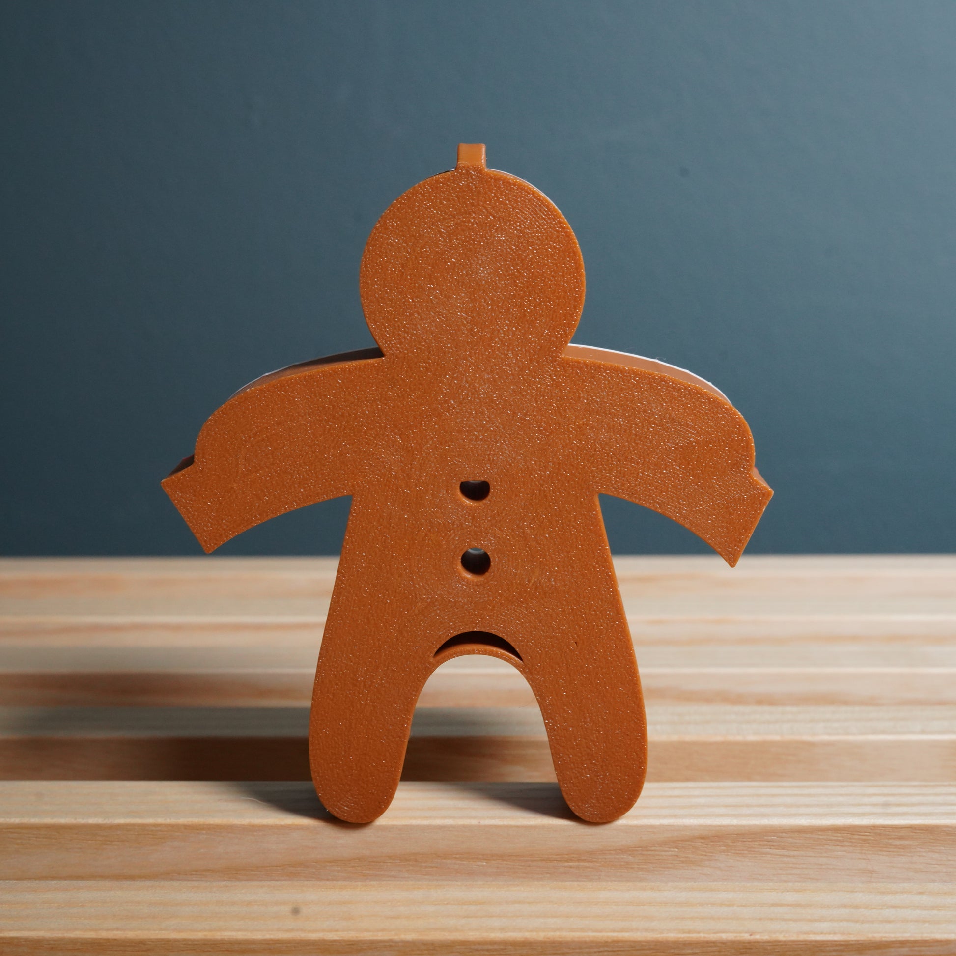 Wooden gingerbread man decoration on a wooden surface with a blue background