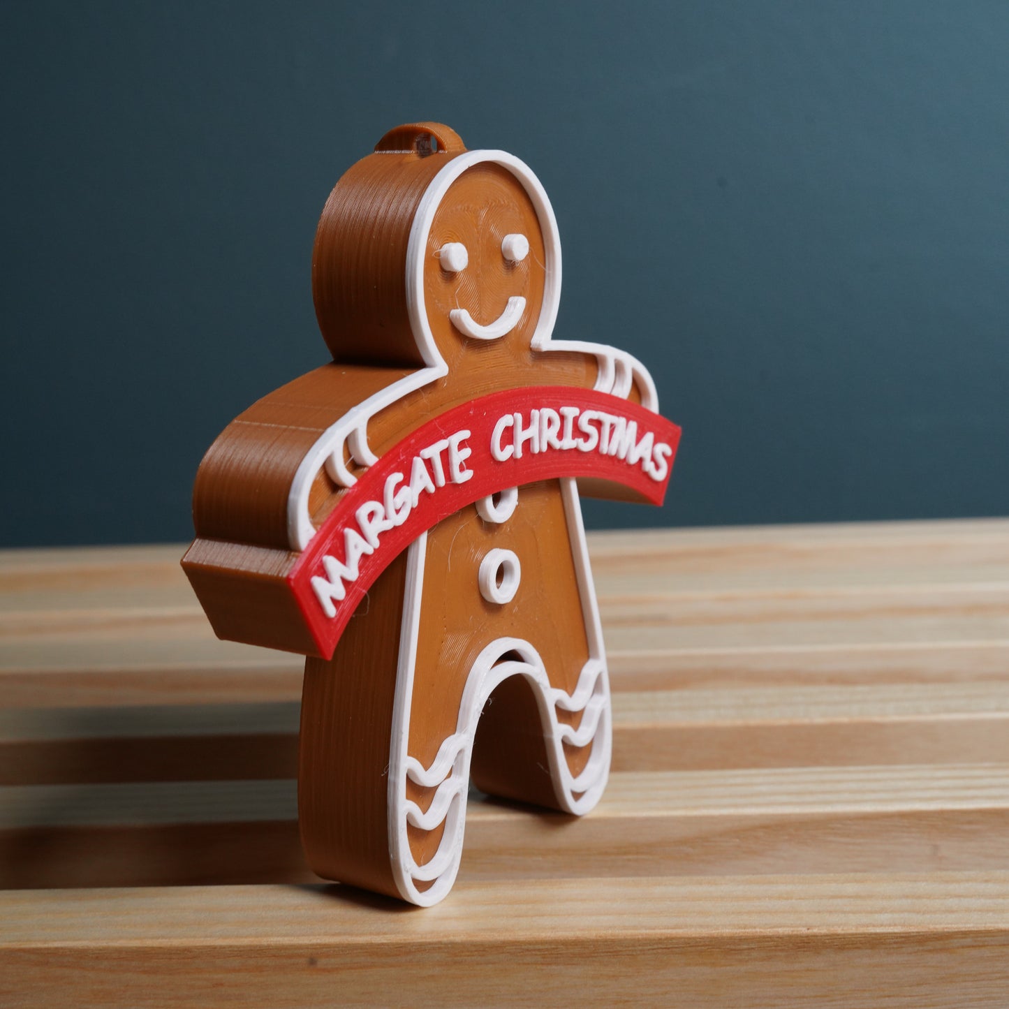 Gingerbread man ornament with 'Margate Christmas' banner on a wooden surface