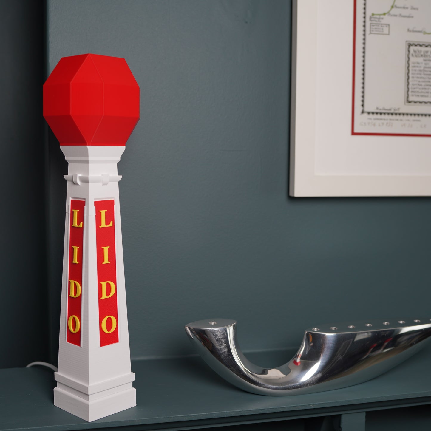 Decorative Margate Lido table lamp with E14 bulb with red and white design on a shelf against a gray wall.