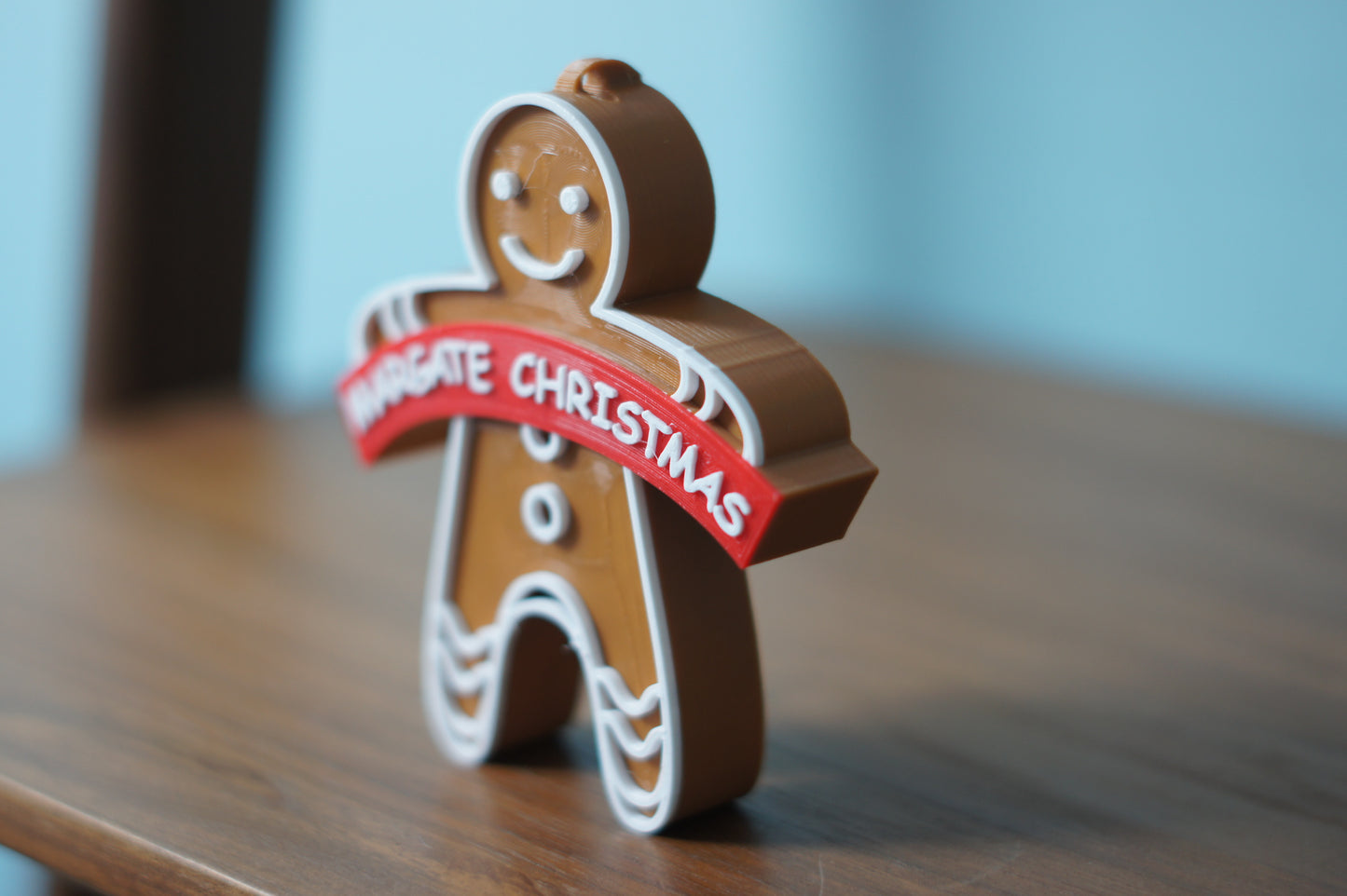 A Christmas ornament featuring a Margate design with a hanging hole on top.