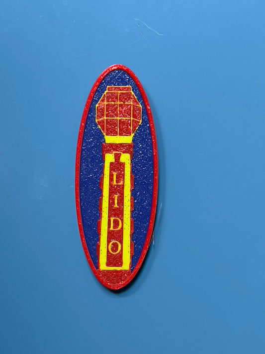 A round blue and yellow magnet with a decorative floral pattern and the word 'LIDO' in the center.