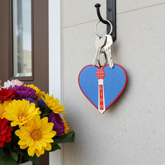Heart-shaped keychain with 'LIDO' branding on a door next to flowers