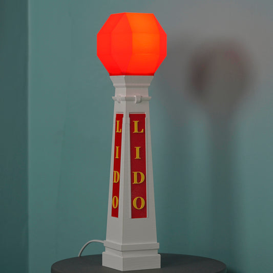 Decorative lamp with red octagonal shade and 'Lido' branding on a dark surface against a gray background
