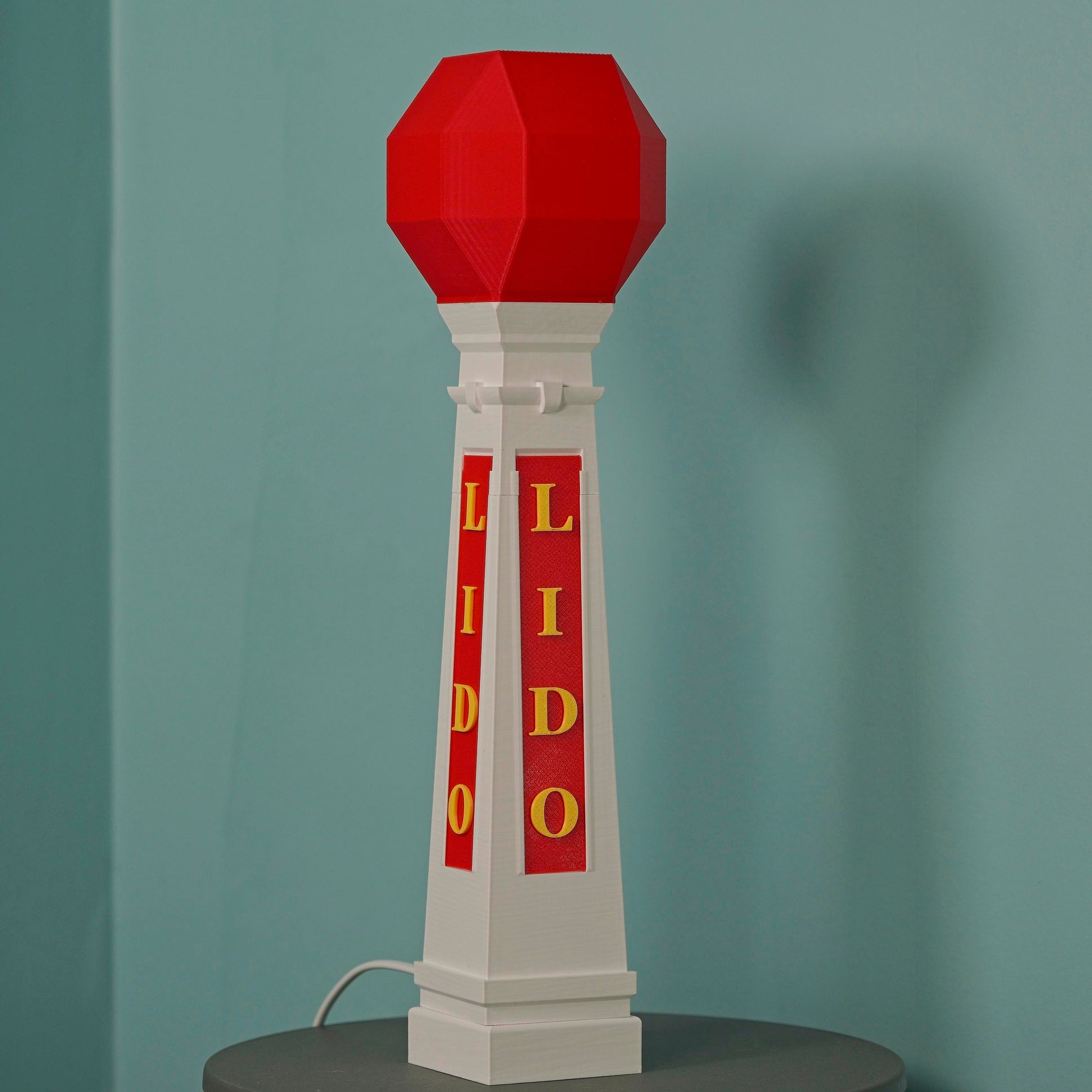 Margate Lido table lamp with E14 bulb with red and white design on a gray surface against a green wall